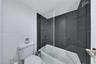 Bathtub featuring a glass shower panel, textured dark wall tiling, and chrome fixtures