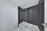 Bathtub with a glass panel, dark charcoal textured wall tile, chrome shower fixtures, and minimalist hardware