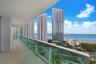 Covered balcony featuring neutral large-format tile flooring and a glass panel railing