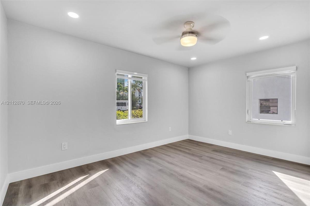 Neutral-toned room featuring wood-finish flooring, recessed lighting, and a ceiling fan with integrated light fixture