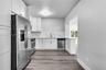 Kitchen featuring white shaker-style cabinetry, stone-patterned backsplash, stainless steel appliances, and wood-finish flooring