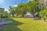 Expansive backyard featuring a concrete patio, established trees, and mature landscaping