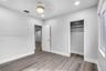 Neutral-toned interior space featuring wood-finish flooring, recessed lighting, a modern ceiling-mounted light fixture, and a reach-in closet