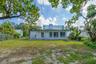 Rear exterior featuring a flat roofline, white siding, large multi-pane windows, and a generous lot with mature trees