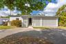 Single-story exterior featuring white stucco finish, decorative concrete breeze block accents, and an asphalt driveway