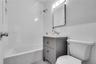 Bathroom featuring a vanity with two storage drawers, white subway tile shower surround, hexagonal floor tile, rectangular wall-mounted mirror, and th