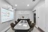 Neutral-toned room featuring a wall-mounted projection screen, overhead projector, recessed lighting, and horizontal window shades