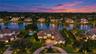 Aerial perspective featuring a waterfront estate with a tile roof, paved circular driveway, manicured landscaping, and a pool