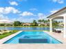 Rectangular swimming pool with an integrated tile-finished spa, expansive stone-paver deck, covered lanai, and waterfront positioning