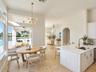Open-concept kitchen featuring an island with stone-surface countertop, undermount sink, and metallic faucet hardware, complemented by natural stone f