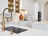 Kitchen featuring white cabinetry with gold-tone hardware, stone countertops, a subway tile backsplash, a high-arc professional style faucet, and buil