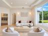 Living area featuring tray ceilings, wainscoting, arched architectural details, polished stone flooring, and expansive floor-to-ceiling windows