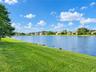 Waterfront lot featuring a grass lawn, rock landscaping, and mature trees