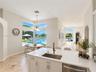Kitchen featuring stone flooring, white cabinetry, a quartz countertop, an undermount stainless steel sink with a metallic faucet, and expansive floor