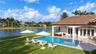 Rear exterior featuring a covered patio, a rectangular swimming pool with an integrated spa, stone-tile decking, and a waterfront location