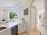 Kitchen area featuring quartz countertops, a built-in wine refrigerator, paneled cabinetry, stone flooring, and an arched entryway