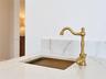 Integrated stone-finish countertop with a coordinating backsplash, featuring a custom metal-finish sink basin and a decorative brass-finish gooseneck 