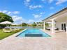 Covered patio with natural stone flooring, swimming pool featuring an integrated spa, and lawn area with water frontage