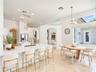 Open-concept interior featuring high ceilings, stone flooring, a center island with stone countertop, brass-finish pendant lighting, and arched archit