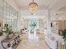 Foyer featuring large-scale polished stone flooring, a multi-tiered crystal chandelier, and a floor-to-ceiling grid-patterned wall mirror