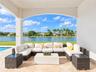 Covered lanai featuring natural stone flooring, arched structural detailing, and water frontage