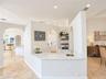 Custom wet bar featuring a stone-look countertop, brass-finish faucet, built-in cabinetry, arched entryways, and stone-finish flooring