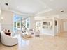Spacious living area featuring polished stone flooring, a tray ceiling, curved bay windows, and a built-in partition wall with an integrated breakfast