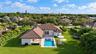 Single-story residence featuring a tile roof, covered patio, integrated swimming pool with spa, and expansive lawn