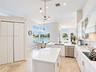 Kitchen featuring white cabinetry, center island with stone-finish countertops, stainless steel appliances, tile flooring, and floor-to-ceiling window