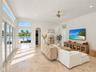 Living area featuring expansive windows, natural stone flooring, high ceilings, an arched doorway, and a brushed gold ceiling fan