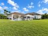 Exterior featuring a tile roof, covered patio with arched supports, built-in swimming pool with masonry deck, and expansive lawn