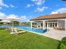 Covered patio with a tile roof, pool and integrated spa with stone tile surround, stone-paved deck, and water frontage