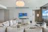 Living space featuring a multi-tiered crystal chandelier, vertical wall paneling, stone flooring, and floor-to-ceiling glass paneling