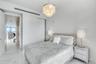 Multi-tiered crystal chandelier with a polished metal finish, polished stone-finish flooring, and built-in closet with sliding doors