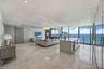 Open-concept living space featuring polished stone flooring, floor-to-ceiling glass wall panels, an integrated kitchen island with stone countertop, r