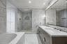 Bathroom featuring extensive stone-surround, frameless glass-enclosed shower with built-in recessed shelving, integrated soaking tub, custom dual-sink