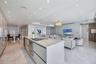 Open-concept interior featuring large-format stone flooring, recessed ceiling lighting, and a central kitchen island with integrated cooktop and built