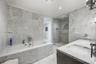 Bathroom featuring floor-to-ceiling stone tile surround, soaking tub with wall-mounted hardware, glass-enclosed walk-in shower, and dual-basin vanity 