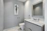 Wall-mounted vanity featuring high-gloss cabinetry, stone countertop with an integrated basin, polished chrome fixtures, and textured wall treatment