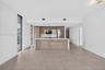 Contemporary kitchen featuring high-gloss cabinetry, a central island with a quartz countertop, stainless steel appliances, and large-format tile floo