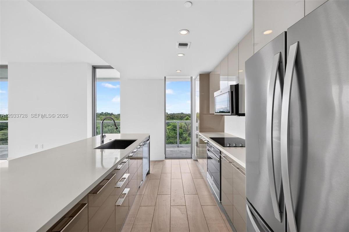 Floor-to-ceiling glass walls, wrap-around balcony with glass railings, ceramic tile flooring, and expansive windows