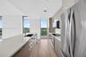 Floor-to-ceiling glass walls, wrap-around balcony with glass railings, ceramic tile flooring, and expansive windows