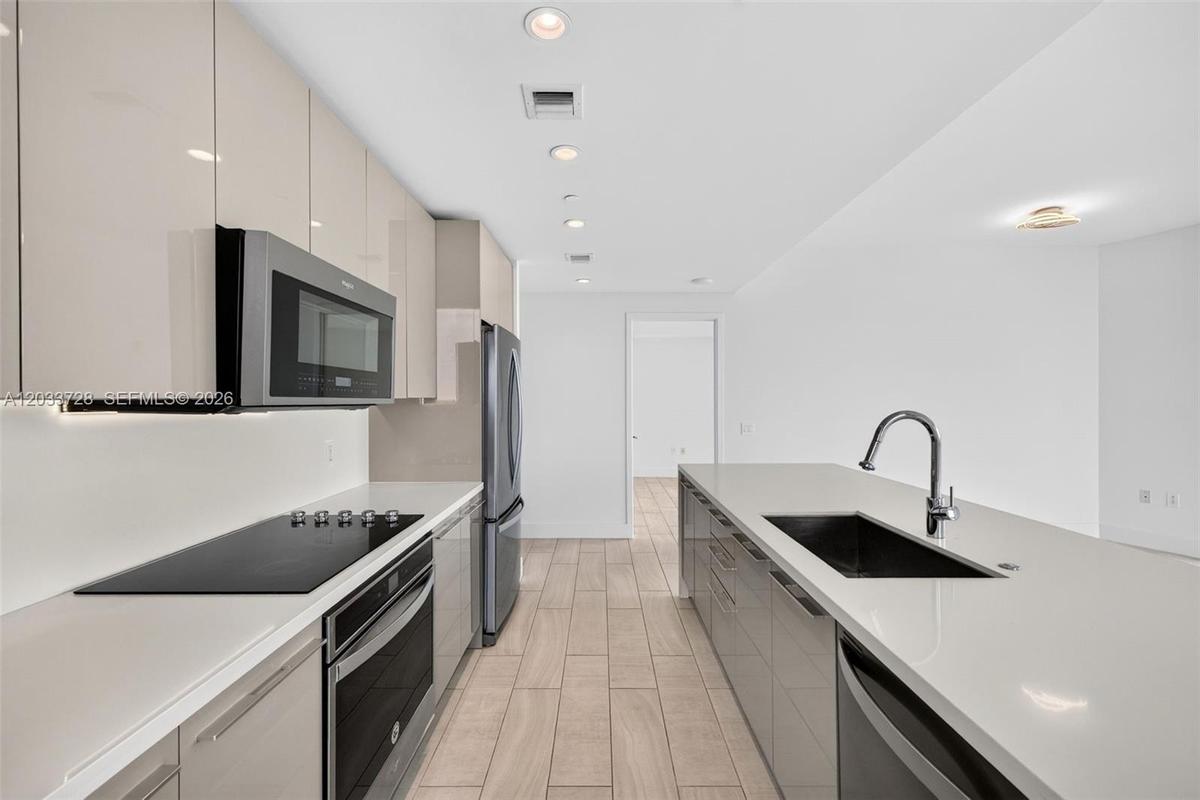 Open floor plan featuring wood-finish tile flooring, floor-to-ceiling glass panel walls, and wrap-around balcony access