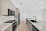 Open floor plan featuring wood-finish tile flooring, floor-to-ceiling glass panel walls, and wrap-around balcony access