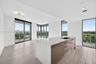 Kitchen island featuring light-toned wood-finish cabinetry, quartz countertops, and an integrated undermount sink with a gooseneck faucet, set against