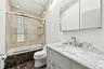 The main-level full hall bath features elegant marble flooring and a skylight that fills the space with natural light.