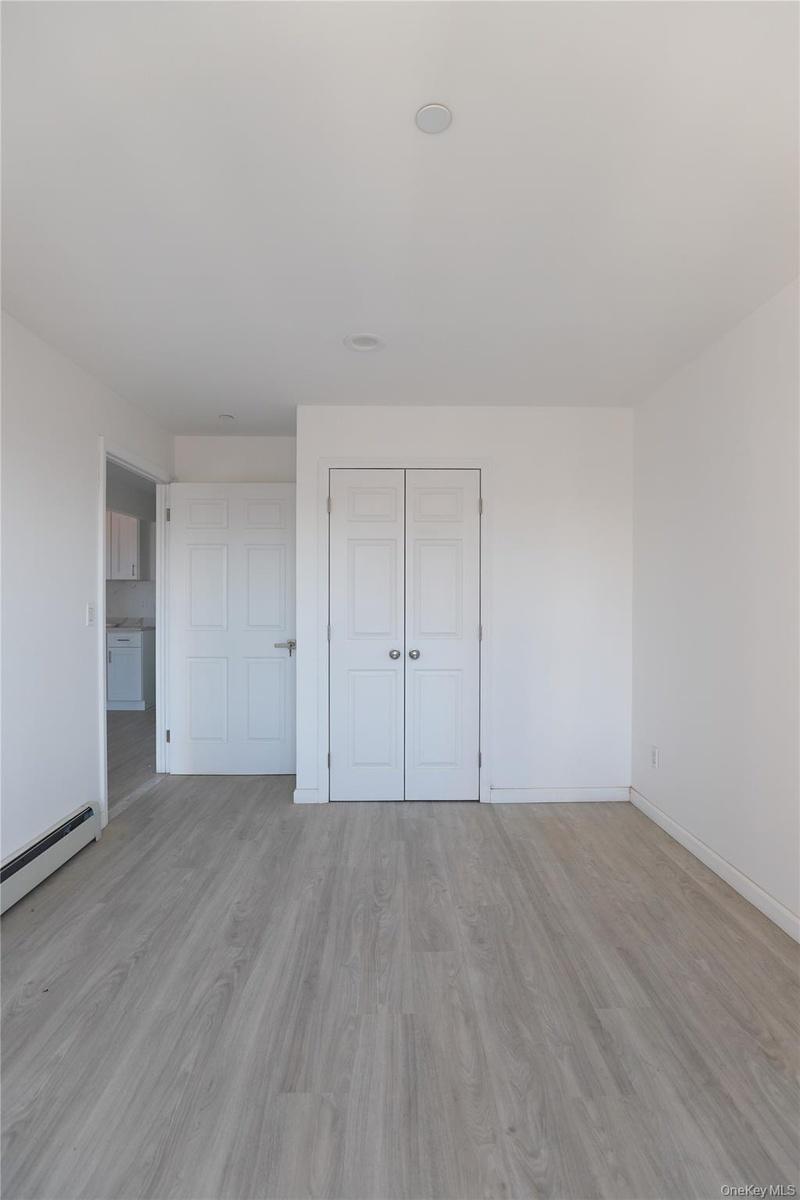 Neutral interior featuring wood-finish flooring, recessed ceiling lighting, and two sets of white six-panel interior doors