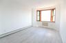 Room featuring wood-finish flooring, a three-panel bay window with wood-trim framing, and neutral wall tones