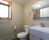 Bathroom featuring full-height wall tile, wood-finish vanity with an integrated sink, polished chrome faucet, and recessed medicine cabinet