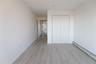 Neutral-toned interior featuring wood-finish flooring, white walls, and a built-in bifold closet